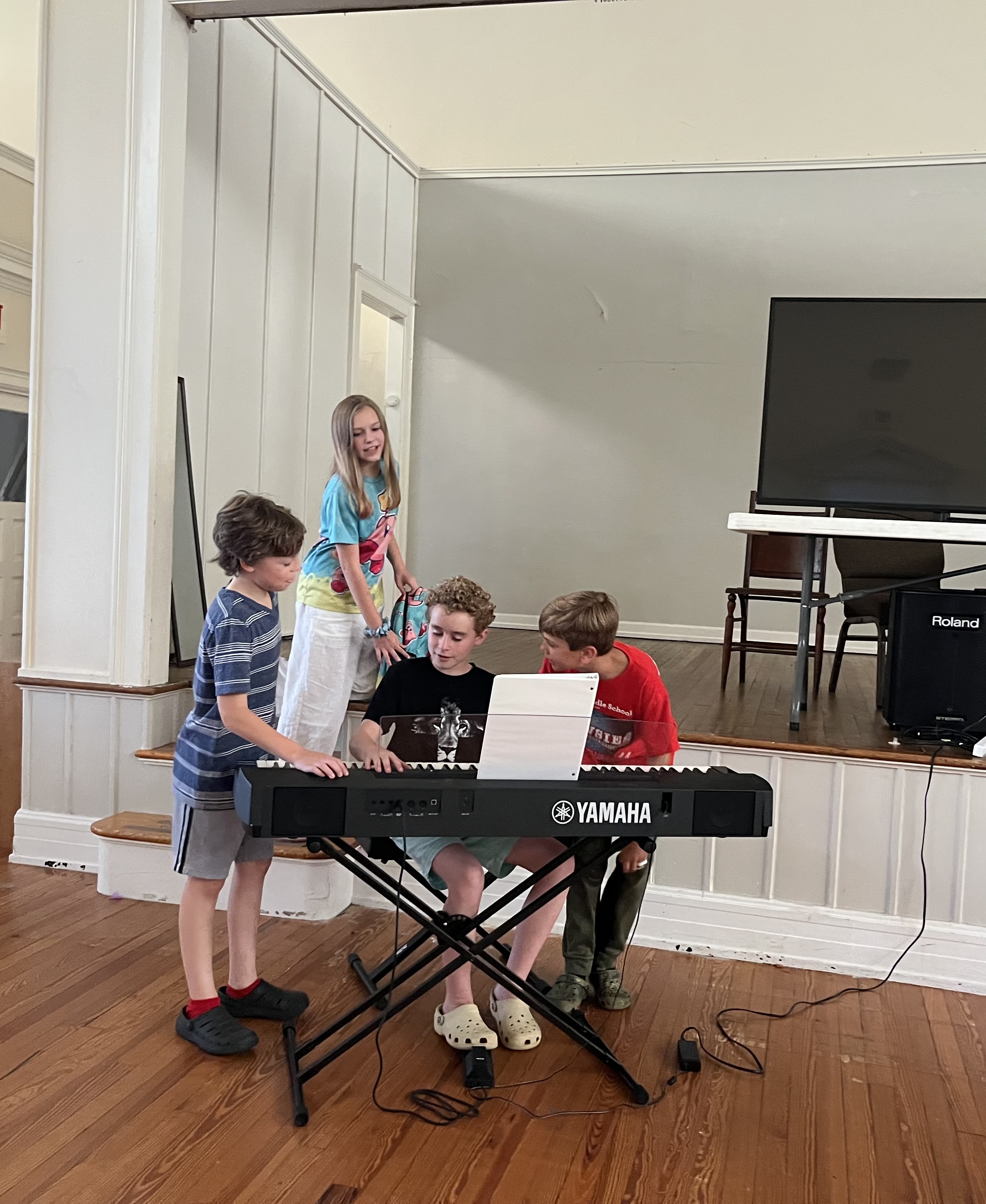 Leland playing piano at a community event while other children watch and listen