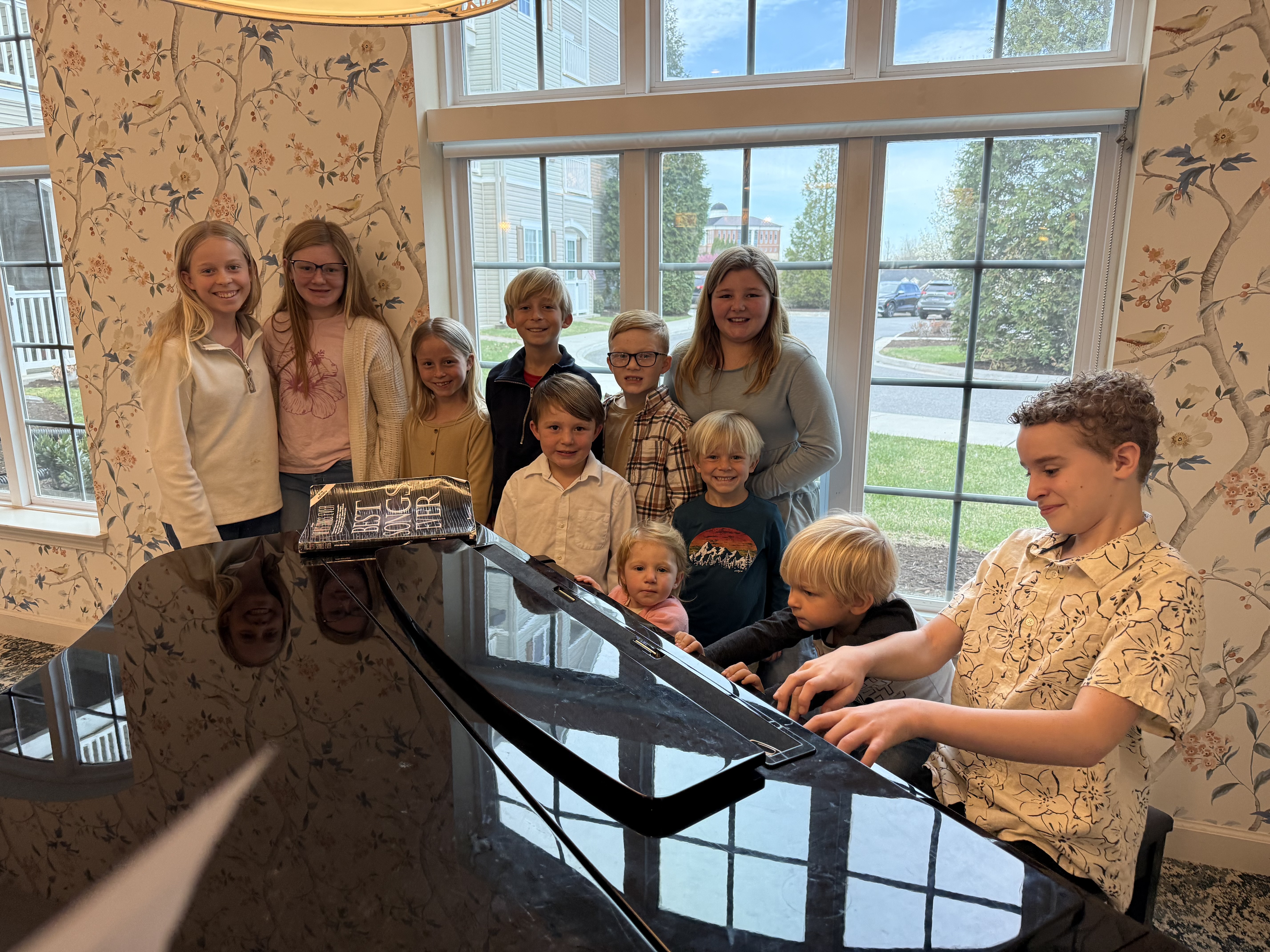 Leland at the piano surrounded by a group of smiling children
