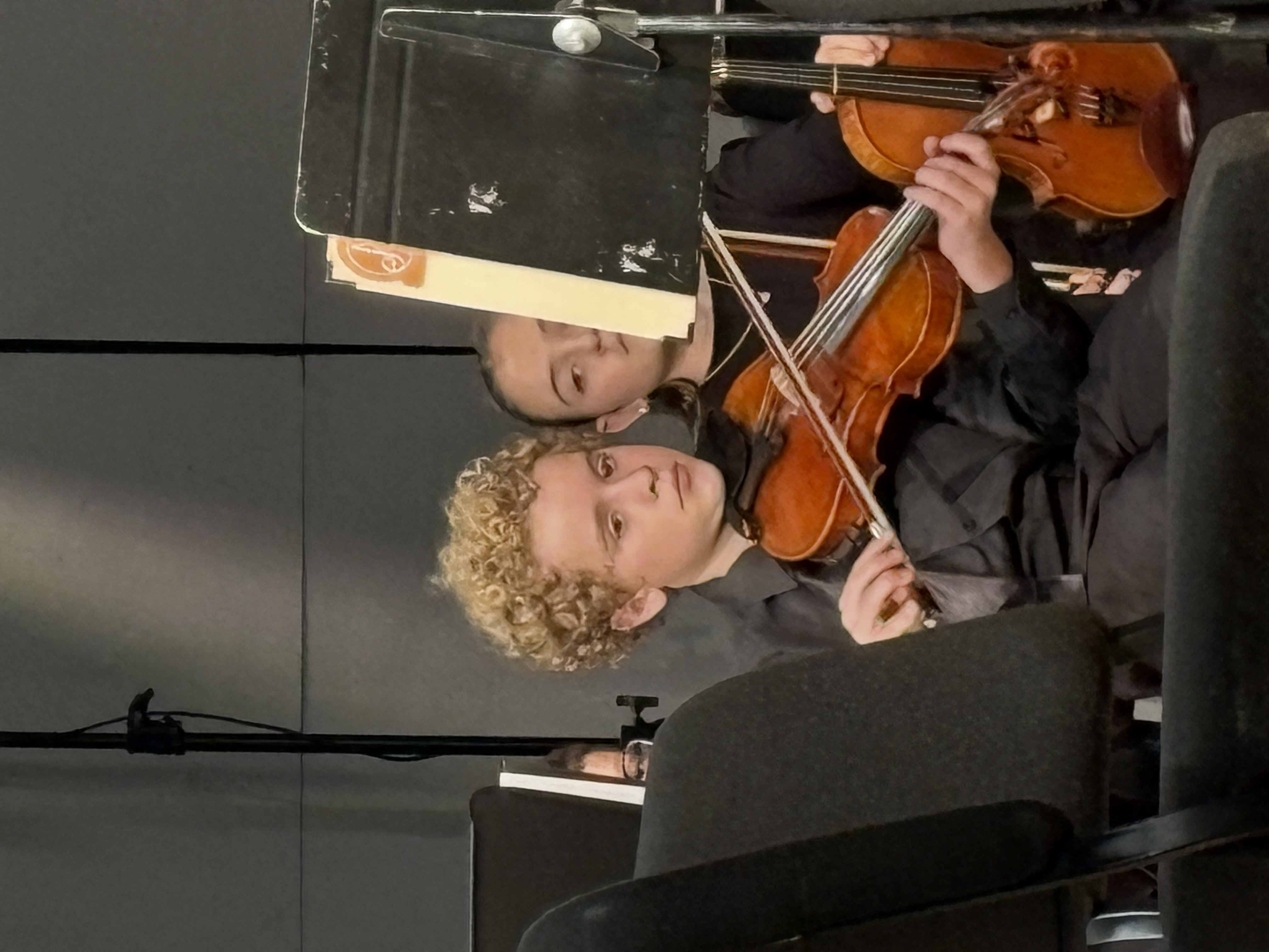 Leland playing violin in concert dress at a rehearsal or performance