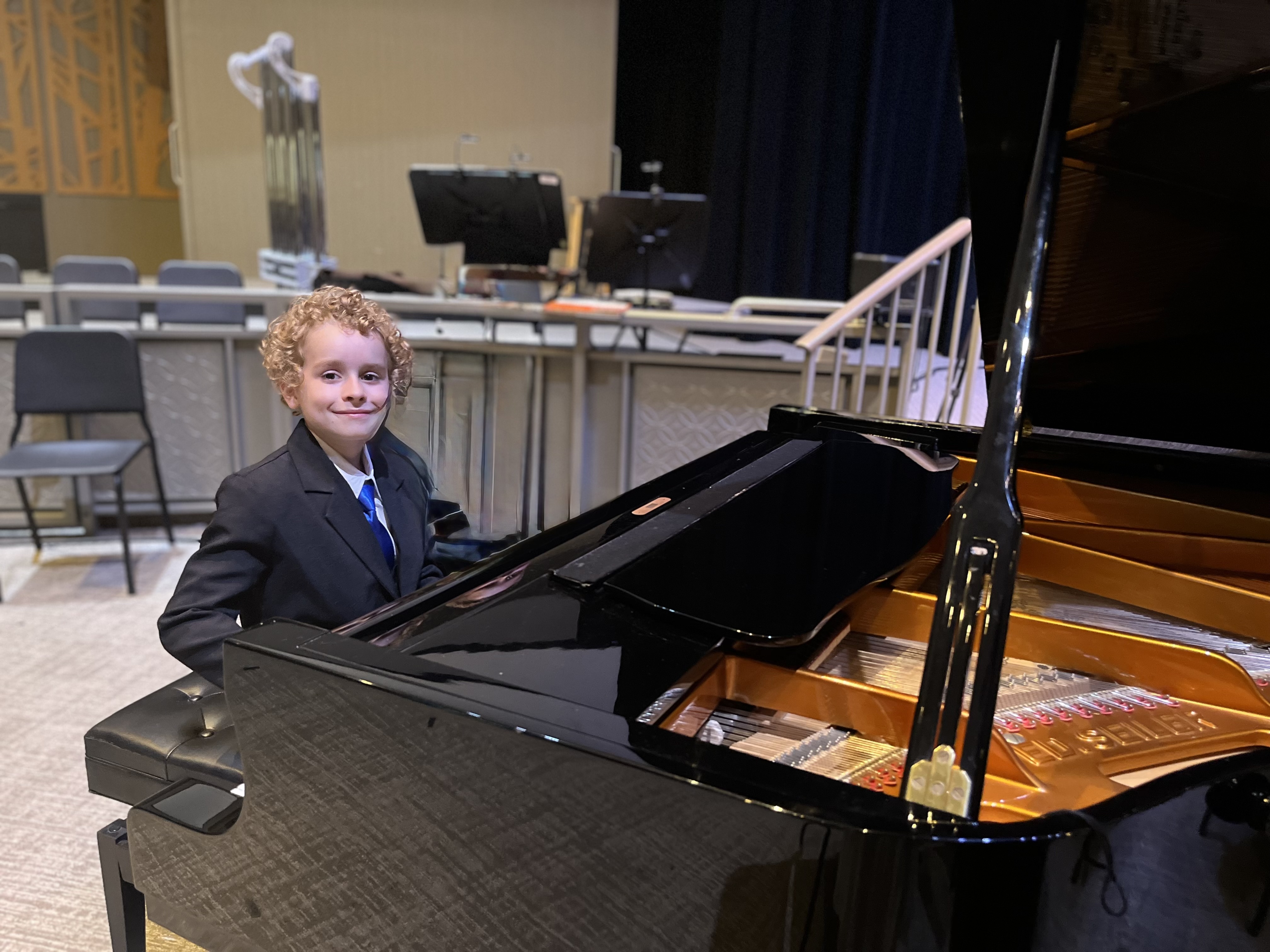 Young Leland in a suit at a Seiler grand piano